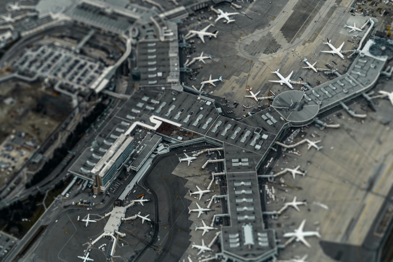 Aerial view of an airport terminal with numerous airplanes parked and various taxiways.