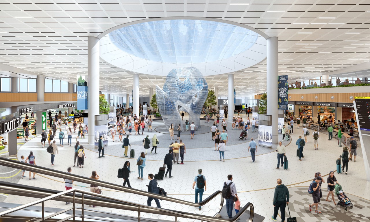 A busy airport terminal with travelers milling about, featuring a large, abstract sculpture in the center and various shops in the background.