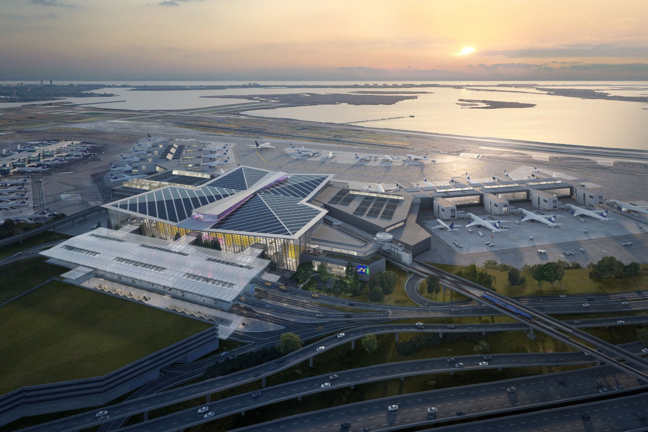 Aerial view of an airport with multiple airplanes and a modern terminal building, set against a sunset backdrop.